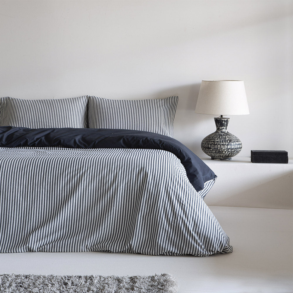 Funda nórdica reversible de algodón percal de 180 hilos extendida sobre cama con almohadas a juego.