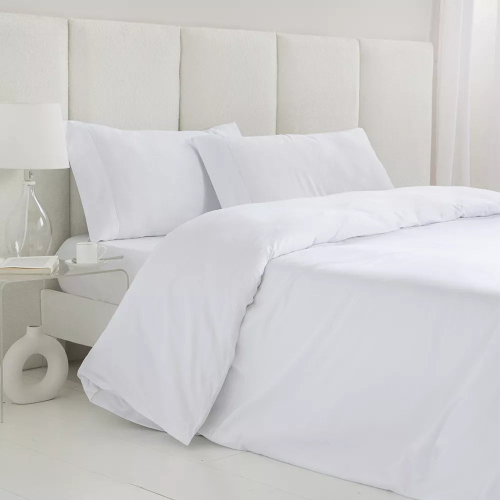 Juego de funda nórdica blanco de satén algodón egipcio de 300 hilos con sábana bajera ajustable y fundas de almohada sobre cama de dormitorio luminoso.