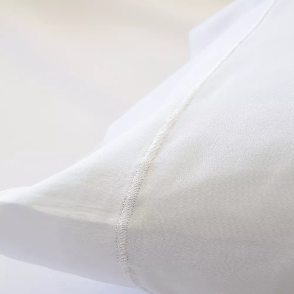 Funda nórdica de satén algodón egipcio blanco de 300 hilos extendida sobre cama con almohadas a juego.