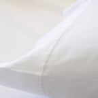 Funda nórdica de satén algodón egipcio blanco de 300 hilos extendida sobre cama con almohadas a juego.