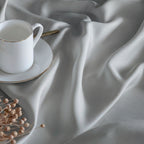 Conjunto de ropa de cama GRIS PERLA fabricado en satén de algodón egipcio de 300 hilos compuesto por funda nórdica, bajera y fundas de almohada.