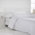 Juego de funda nórdica blanco de satén algodón egipcio de 400 hilos con sábana bajera ajustable y fundas de almohada sobre cama de dormitorio luminoso.