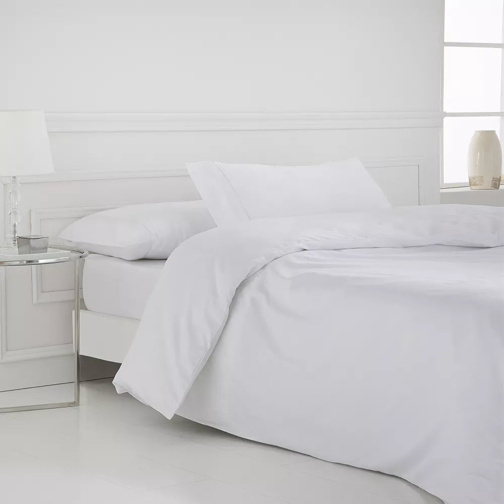 Juego de funda nórdica blanco de satén algodón egipcio de 400 hilos con sábana bajera ajustable y fundas de almohada sobre cama de dormitorio luminoso.
