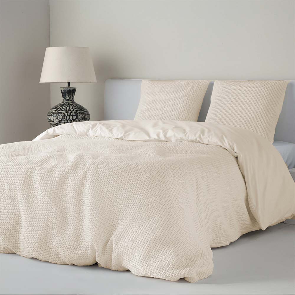 Funda nórdica beige de tejido bafle nido de abeja con textura decorativa, caída natural y estilo elegante sobre cama de dormitorio.