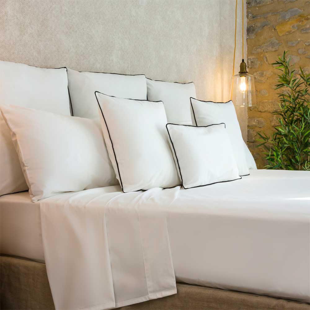 Sábana blanca de algodón orgánico con tejido suave, transpirable y acabado natural, presentada sobre una cama de estilo contemporáneo que destaca la calidad y frescura del material.