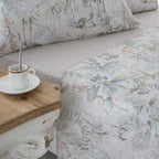 Juego de cama beige de satén algodón 200 hilos con diseño estampado en la sábana superior y bajera lisa coordinada, de textura sedosa y aspecto refinado.