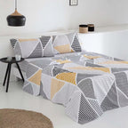 Juego de sábanas de poliéster y algodón compuesto por sábana encimera, bajera ajustable y funda de almohada, con tejido suave, resistente, transpirable y de fácil mantenimiento, presentado sobre una cama de estilo contemporáneo.
