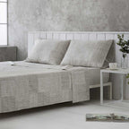 Ropa de cama gris y beige confeccionada en algodón orgánico de alta calidad, agradable al tacto y respetuosa con el medio ambiente.