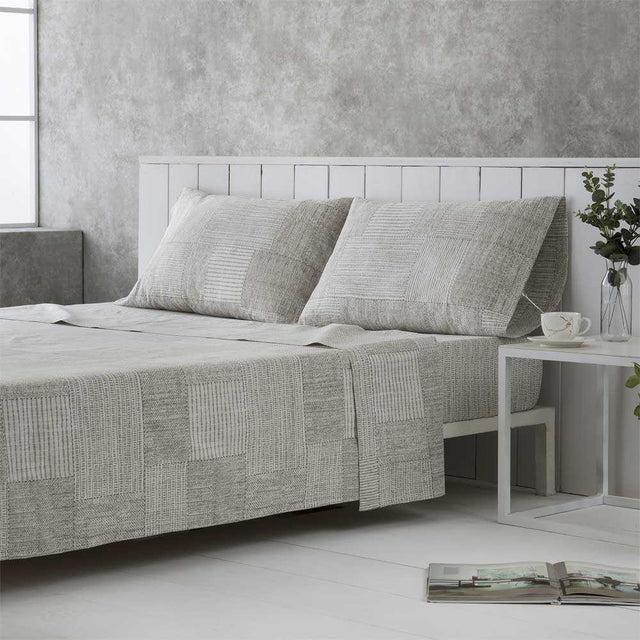 Ropa de cama gris y beige confeccionada en algodón orgánico de alta calidad, agradable al tacto y respetuosa con el medio ambiente.