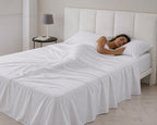 Cama vestida con juego de sábanas blancas de satén 400 hilos en algodón egipcio de alta calidad y brillo sutil.
