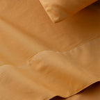 Conjunto de sábanas de percal de algodón de 200 hilos MOSTAZA compuesto por sábana encimera, bajera ajustable y funda de almohada, con acabado liso y elegante.