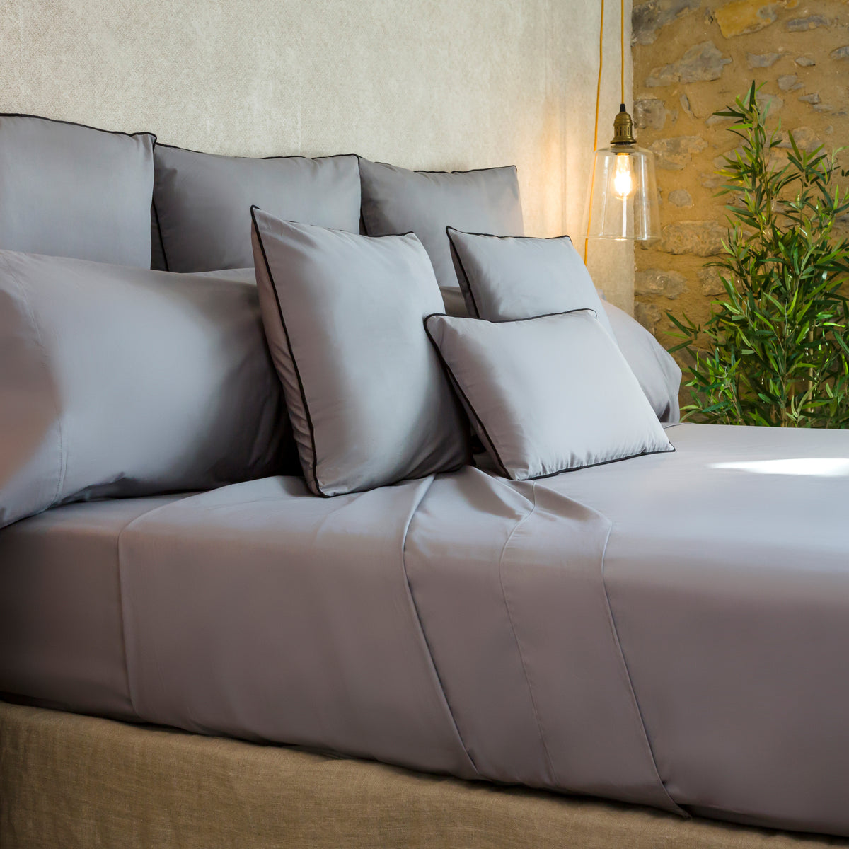 Sábana gris de algodón orgánico con tejido suave, transpirable y acabado natural, presentada sobre una cama de estilo contemporáneo que destaca la calidad y frescura del material.