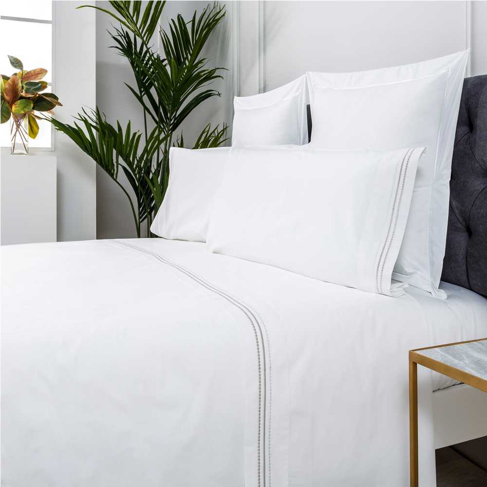 Sábana blanca bordada confeccionada en percal de algodón 200 hilos, suave, fresca y elegante para cualquier dormitorio.