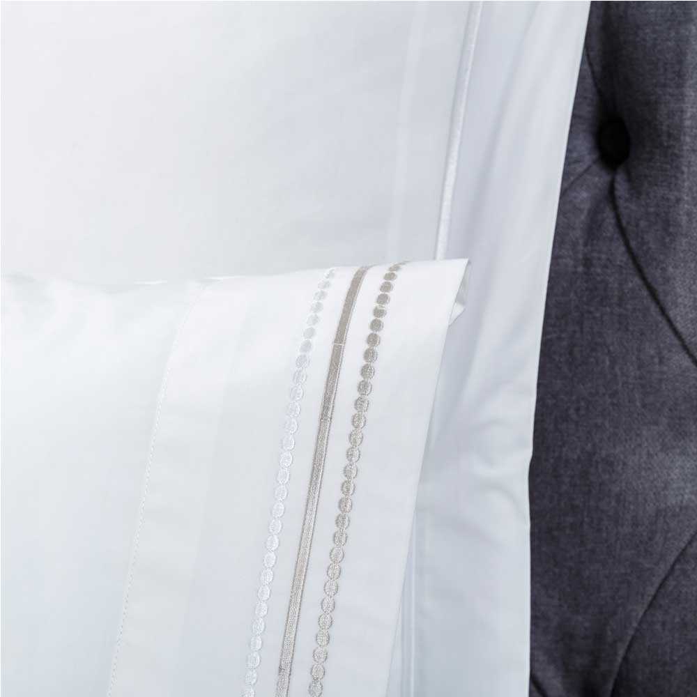 Sábana encimera blanca bordada en percal de algodón 200 hilos, ideal para un dormitorio elegante y luminoso.